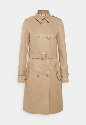 Beżowy płaszcz trench z podwójnym zapięciem, zapięciem na guziki, paskiem w talii i dwoma bocznymi kieszeniami; posiada wstążkową podszewkę.