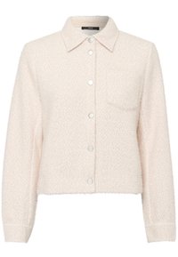 Chaqueta texturizada de color beige claro con mangas largas, cuello puntiagudo, botones de presión en la parte delantera y un bolsillo en el pecho del lado izquierdo.