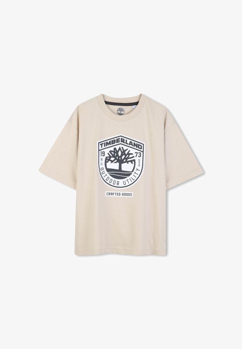 T-shirt beige à manches courtes en coton, arborant un grand logo Timberland imprimé en noir avec un design d’arbre et l’inscription "Crafted Goods".