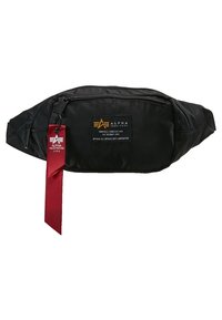 Svart midjeväska från Alpha Industries med två dragkedjefack och en röd märkesklädesetikett hängande från den vänstra dragkedjan.