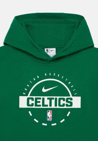 Moleton verde feito de tecido macio, com um logótipo central branco onde está a palavra "CELTICS", o swoosh da Nike e o logótipo da NBA. Design simples e redondo.