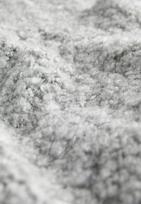 Texture douce et bouclée de laine grise avec des fibres étroitement compactées créant une surface duveteuse et dense.