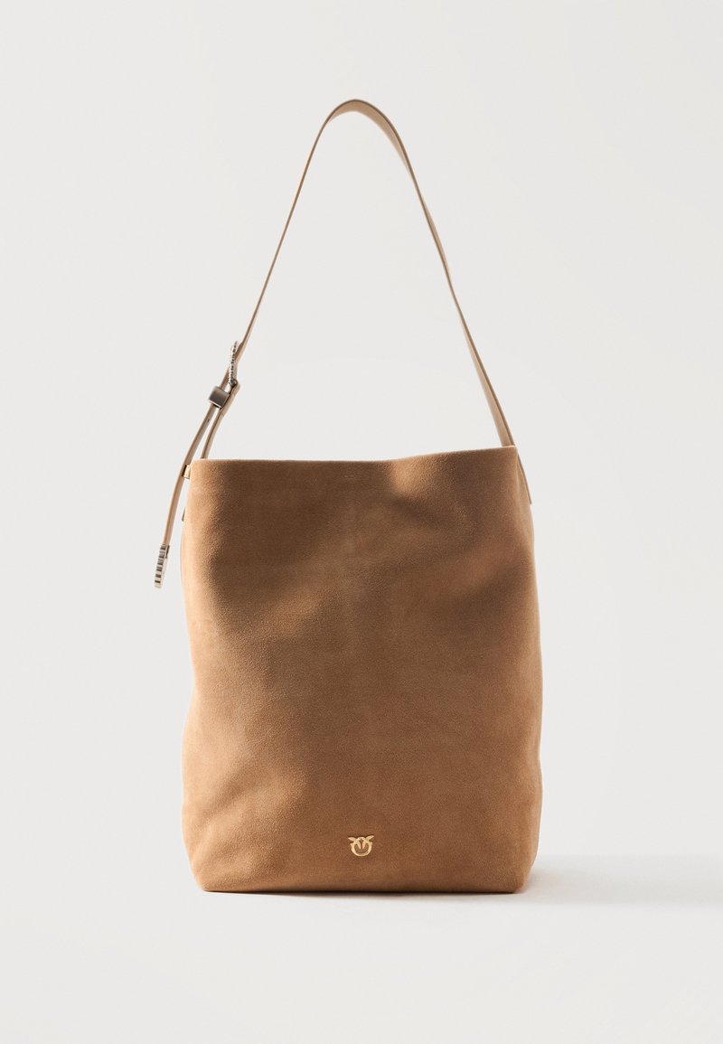 Μαλακή καφέ δερμάτινη τσάντα ώμου με ένα ρυθμιζόμενο ιμάντα και μικρό χρυσό λογότυπο κοντά στο κάτω κέντρο, σε λευκό φόντο.
