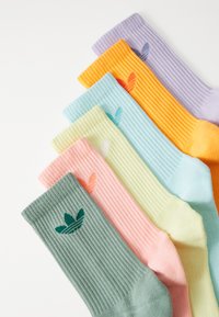 Pruhované ponožky v pastelových farbách: zelená, ružová, žltá, modrá, oranžová, fialová. Každá ponožka má mal�é logo v kontrastnej farbe.