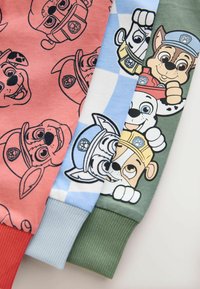Three children's sweatshirt sleeves: red with puppy print, light blue with checkerboard, and green featuring cartoon dog characters.