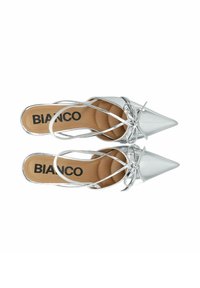Chaussures à talons hauts en argent avec un bout pointu, dotées de brides croisées et d'un détail en nœud. Surface lisse et brillante avec une semelle intérieure beige.
