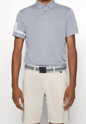 Mand iført lysegrå polo med hvid stribe på ærmet og beige shorts med gråt bælte med sort spænde