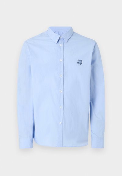Ανοιχτό μπλε πουκάμισο με μακρύ μανίκι και κουμπιά, γιακά και μικρό κεντητό λογότυπο κεφαλής λύκου στο αριστερό στήθος.