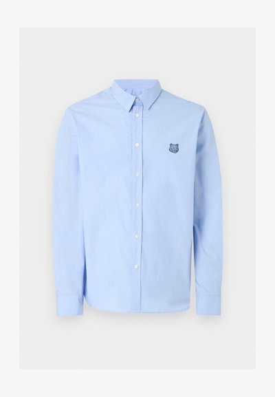 Ανοιχτό μπλε πουκάμισο με μακρύ μανίκι και κουμπιά, γιακά και μικρό κεντητό λογότυπο κεφαλής λύκου στο αριστερό στήθος.