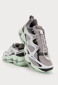 Baskets en maille grises et blanches avec une semelle vert menthe, présentant un design flexible, un accent GORE-TEX et des lacets élastiques.
