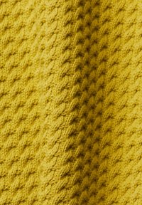 Tissu jaune tricoté avec un motif texturé en torsades, présentant des plis et des ombres qui mettent en valeur sa qualité de matériau doux et épais.