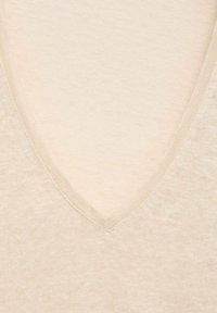 Pull en V beige avec un tricot doux et texturé. Présente un motif subtil légèrement chiné et des bords finis.