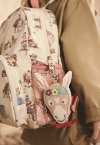 Rucsac din material lucios alb, cu modele colorate de animale și o buzunar din plasă roz. Atașat este un pouch bej în formă de cap de cal.