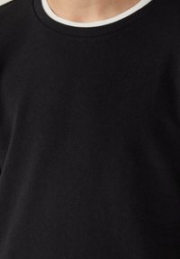 Zwarte katoenen sweatshirt met een geprofileerde stof, voorzien van een geribde halslijn en een witte binnenkraag. Eenvoudig, klassiek ontwerp.