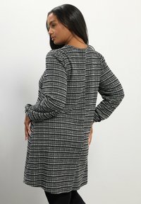 Schwarz-weiße kariertes Tunika-Kleid mit langen Ärmeln, strukturierter Stoff, runder Ausschnitt und lässiger Schnitt, der bis zur Mitte des Oberschenkels reicht.