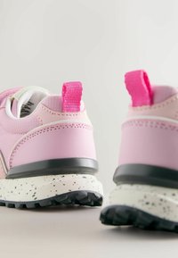 Rózsaszín sportcipő texturált szövet felsőrésszel, megerősített sarokkal és gumis, pettyezett talppal. A hátoldalon rózsaszín húzófül található.