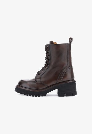 Bottines en cuir marron foncé à lacets avec une semelle et un talon épais en caoutchouc noir, dotées d'une languette à l'arrière.