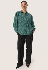 Groene button-up shirt met een gestructureerd patroon, gecombineerd met zwarte op maat gemaakte broek en zwarte puntige hakken. Glad stof, ontspannen pasvorm.