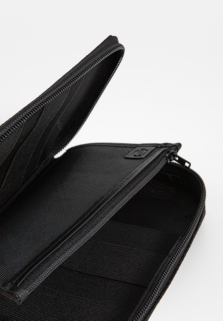 Portafoglio nero con zip realizzato in materiale durevole, dotato di più scomparti per carte e un interno liscio con un'esterno texturizzato.