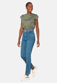 Alyvuogių žalia trumpų rankovių palaidinė derinama su aukšto liemens mėlynomis džinsinėmis kelnėmis ir baltais sportbačiais su žaliais akcentais. Paprastas dizainas, glotnaus paviršiaus.