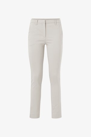Pantalones ajustados beige con cremallera, bolsillos delanteros y un corte slim. La tela tiene una textura suave y un ligero brillo.