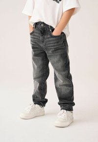 Svarta denimbyxor med en urtvättad yta, med en klassisk femficksdesign och knappstängning fram. Stylen kompletteras med vita sneakers.