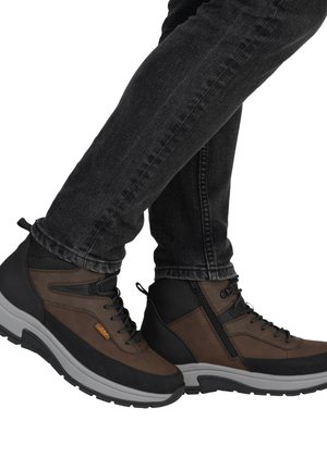 Braune und schwarze Knöchelstiefel aus Leder und synthetischem Material, mit gepolstertem Kragen, Schnürdesign und einer dicken grauen Sohle.