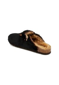 Mocassin noir avec doublure en fourrure, intérieur doux, semelle en liège plate et design dos ouvert. Accentué par un dessus texturé et des teintes naturelles.