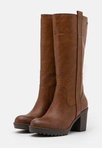 Bottes mi-hautes en cuir synthétique marron avec un talon épais, présentant une texture lisse et un détail minimaliste de coutures, conçues pour durer.
