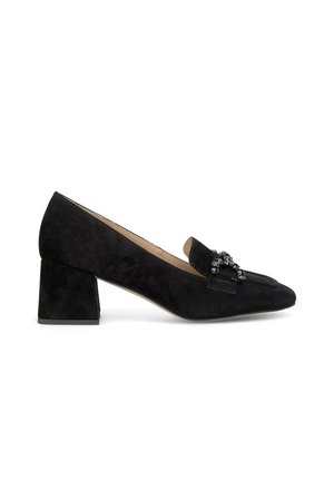 Mocassins à talons carrés en suede noir avec un bout pointu, présentant un ornement décoratif noir sur la tige. Design élégant et texturé.