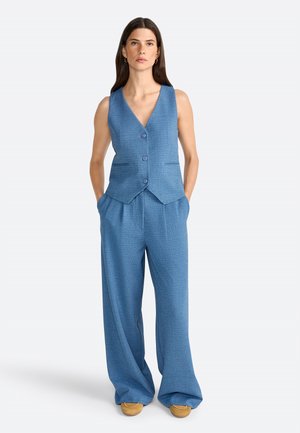 Blue textured vest with a V-neck and three buttons, paired with wide-leg trousers in the same fabric. Both pieces feature pockets.