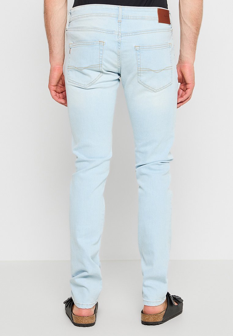 Hellblaue Jeans im Slim-Fit, mit zwei Gesäßtaschen, dezenten Nähten und einem braunen Lederpatch am Bund.