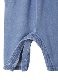 Denim-Overall in Hellblau, mit einem Druckknopfverschluss am Bein, kurzen Ärmeln und einer strukturierten Oberfläche mit einem leichten Glanz.