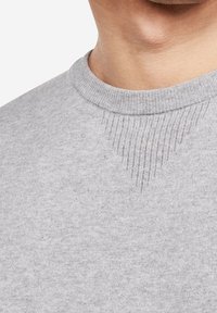 Grauer Sweatshirt mit rundem Halsausschnitt, geripptem Kragen und strukturiertem Einsatz an der Schulter. Das Material wirkt weich und glatt.
