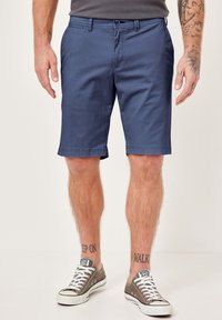 Navy blue shorts in lightweight fabric with a flat front, belt loops, and side pockets. Paired with gray sneakers with white accents.