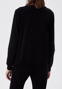 Schwarzer Pullover mit langen Ärmeln, rundem Halsausschnitt, gerippten Bündchen und Saum, weicher Textur, schlichtem Design ohne sichtbare Logos oder Verzierungen.