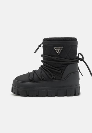 Black quilted waterproof boot with a faux fur collar, rubber sole, and lace detailing. Features a logo plaque on the side.
