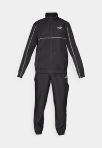 Black tracksuit with zip-up jacket and elasticated waist pants. Features white piping and Puma logo on the chest and leg. Smooth fabric texture.