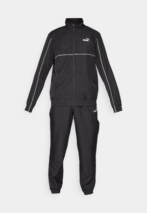 Schwarzer Trainingsanzug mit Reißverschlussjacke und elastischen Bundhosen. Mit weißen Paspeln und Puma-Logo auf Brust und Bein. Glatte Stofftextur.