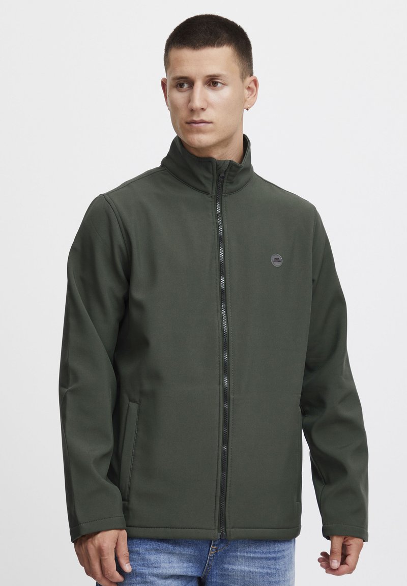 Dark green zip-up jacket with a high collar, made from a smooth, sturdy fabric. Features side pockets and a small logo on the chest.