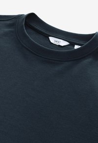 Dark blue cotton t-shirt with a crew neckline and a label reading "NEXT, Regular Fit." Smooth texture and simple design, no patterns.
