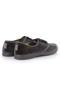 Zapatillas de ante negro con puntera redondeada, acentos grises, diseño de cordones y suela de goma texturizada. Marca visible en la etiqueta del talón.