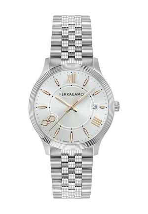 Srebrny zegarek ze stali nierdzewnej z srebrną tarczą, złotymi akcentami, znacznikami w postaci rzymskich cyfr oraz teksturowanym wzorem bransolety. Posiada wyświetlacz daty.