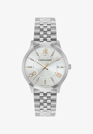 Sølv rustfrit stål ur med en sølv skive, guld accenter, romerske tal markører og et struktureret armbåndsdesign. Har dato display.