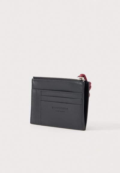 Μαύρη δερμάτινη θήκη καρτών με πολλές θήκες για κάρτες, ένα διαμερισμα με φερμουάρ και κόκκινο τμήμα έλξης φερμουάρ.