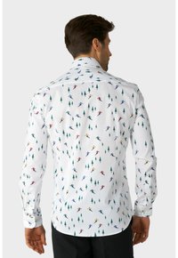 Balta marškiniai su slidinėjimo raštu, kuriame yra įvairiaspalvių slidininkų ir žalių medžių, pagaminti iš lygaus audinio su įprasta apykakle ir mygtukų užsegimu.