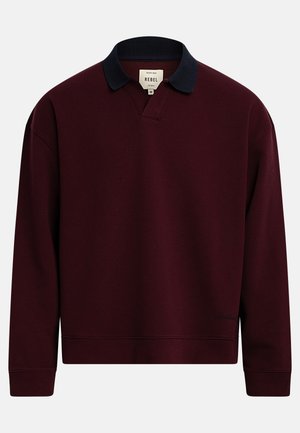 Bluza polo lungă bordo închis cu mâneci lungi, guler negru și manșete rib, inscripționată "Rebel" în interiorul gulerului.