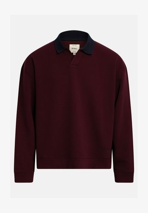 Polo en maille à manches longues de couleur bordeaux foncé avec col côtelé noir et poignets côtelés, étiquette "Rebel" à l'intérieur du col.