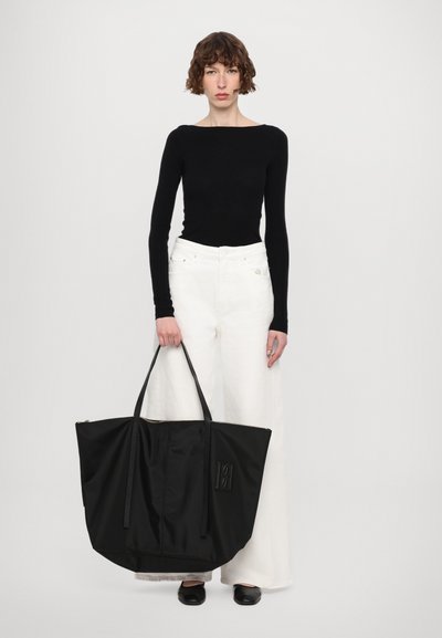 Must must kand, millel on kaks pikka sangat, lai alus ja esiküljel diskreetne reljeefne logo. Sile tekstuur, minimalistlik disain.