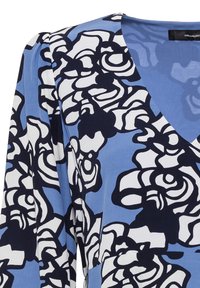 Modré květinové šaty s výstřihem do V, dlouhými rukávy a vzorem velkých bílých květin se tmavě modrým obrysem. Hladký textilní povrch.